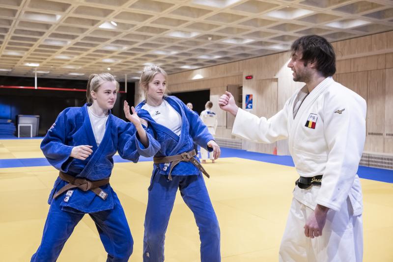Twee meisjes krijgen uitleg over judo van leerkracht in de sporthal van Topsportschool Antwerpen.