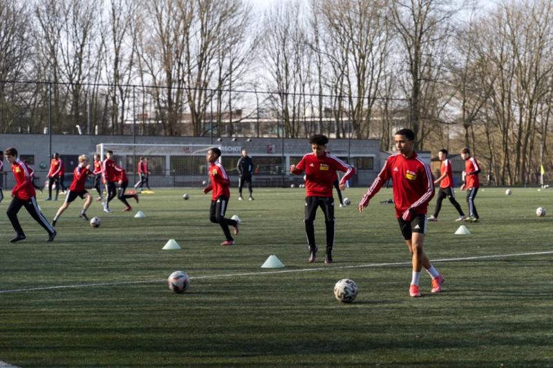 Jongens zijn aan het voetballen op een voetbalveld van Topsportschool Antwerpen.